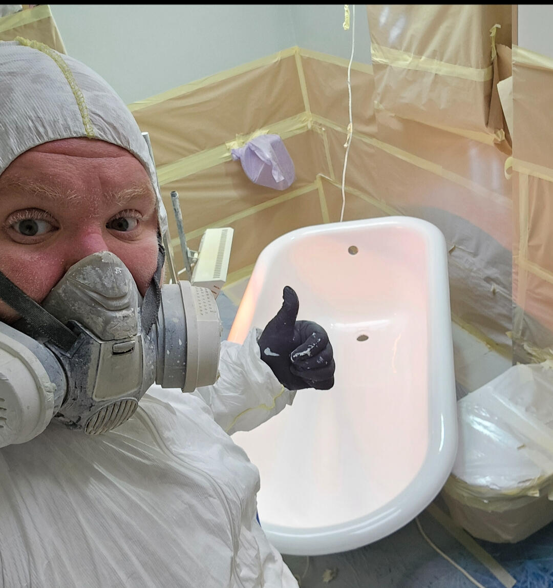 photo of glossy baths owner photo of glossy baths re-enamelling owner Seamus with a thumbs up, in ppe, in a room full of masking up and a completed bath in Swindon
